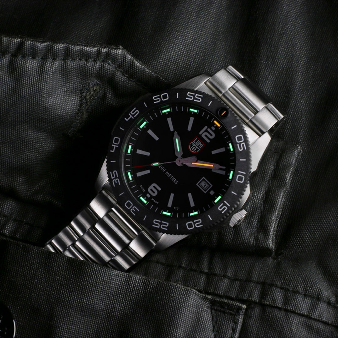 Silver watch with black dial on a dark fabric background
