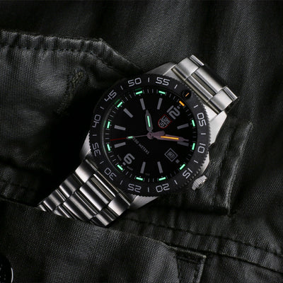 Silver watch with black dial on a dark fabric background