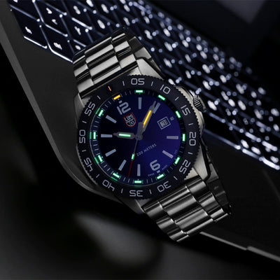 Luxury watch with a blue face and silver band on a dark background